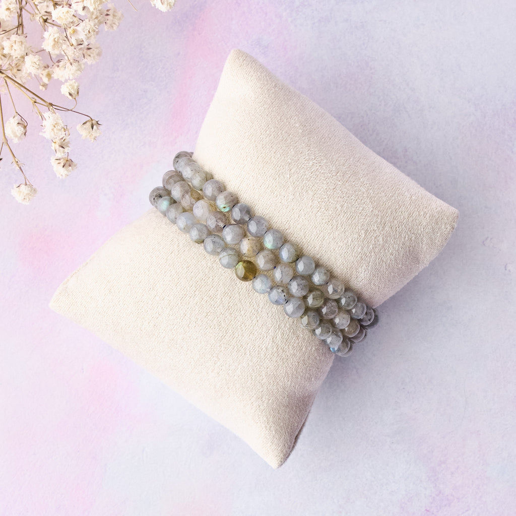 Tre labradoritarmband med 6 mm pärlor, placerade på en liten smyckeskudde.