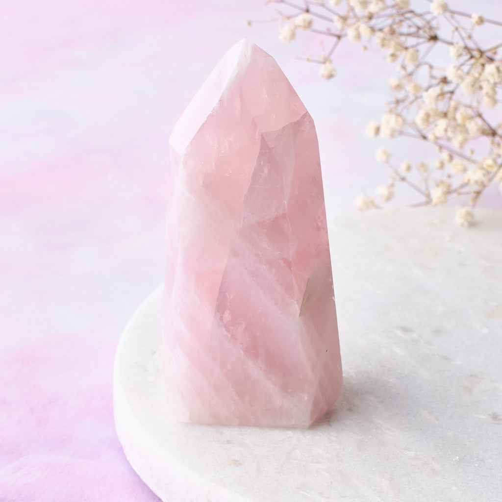 En närbild framifrån på ett rosenkvartstorn, fotograferat mot en vit bakgrund med rosa-lila toner.