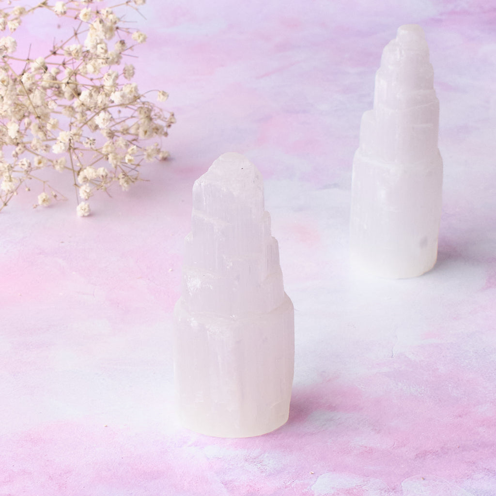 Två små selenittorn sedda framifrån, fotograferade mot en rosa-lila bakgrund.